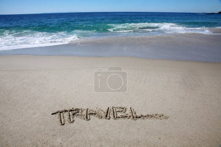 Foto de Travel written in the sand on the beach.  message handwritten on a smooth sand beach - Imagen libre de derechos