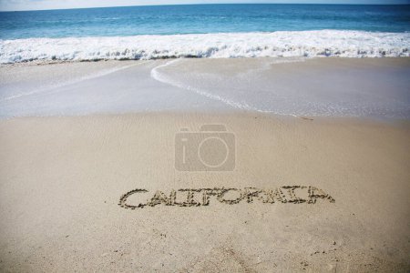 Foto de California  written in the sand on the beach.  message handwritten on a smooth sand beach - Imagen libre de derechos