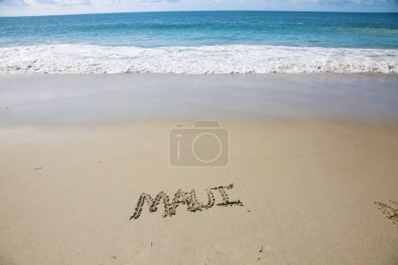 Téléchargez les photos : Maui   written in the sand on the beach.  message handwritten on a smooth sand beach - en image libre de droit