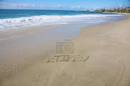 Foto de Retired  written in the sand on the beach.  message handwritten on a smooth sand beach - Imagen libre de derechos