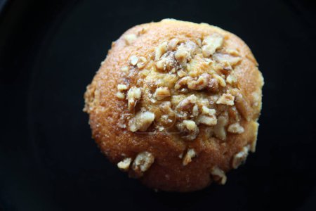 Foto de Muffin. Banana Walnut Muffin on a black plate. Delicious Homemade Banana Bread Pecan Nut Muffin. Fresh baked banana walnut muffin. Breakfast Pastry. Isolated on black. People world wide love muffins. - Imagen libre de derechos