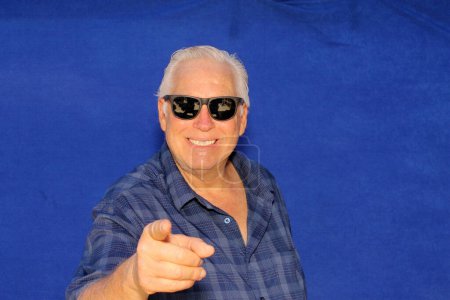 Photo for Photo Booth. Photo Booth Pictures. A man smiles and poses while in a Photo Booth with a Blue Velvet Background. A handsome man laughs, smiles, and poses with crazy props while in a Photo Booth. - Royalty Free Image
