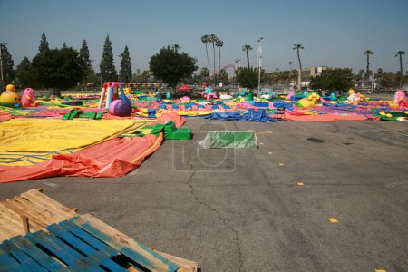 Foto de Buena Park, California - Estados Unidos - Abril - 27-2023: Juguetes inflables en un estacionamiento. juguetes inflables inflables sin inflar para los niños. castillos inflables coloridos del partido de los niños, diapositivas, y casas del rebote. - Imagen libre de derechos
