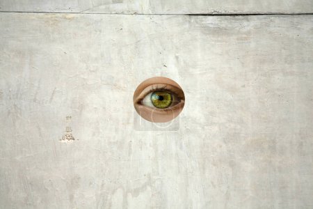 Photo for Hole in the wall. A Human Eye looks through a Hole in a Cement Wall. Hidden behind a wall. Sealed in Concrete. Secret Spying while hidden behind a wall. Eye see you. - Royalty Free Image