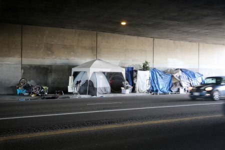 Foto de Long Beach, California - Estados Unidos - 16 de abril de 2023: Refugio para personas sin hogar contra una pared en un carril de tráfico. La falta de vivienda se ha convertido en un problema nacional para la sociedad y las personas afectadas por la pobreza.. - Imagen libre de derechos