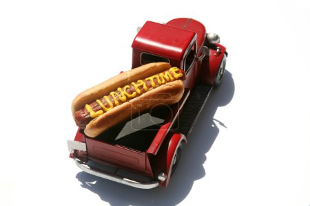 Téléchargez les photos : Hotdog dans un camion dans son chignon. avec le texte écrit en moutarde jaune. Isolé sur blanc. - en image libre de droit