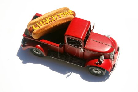 Téléchargez les photos : Hotdog dans un camion dans son chignon. avec le texte écrit en moutarde jaune. Isolé sur blanc. - en image libre de droit