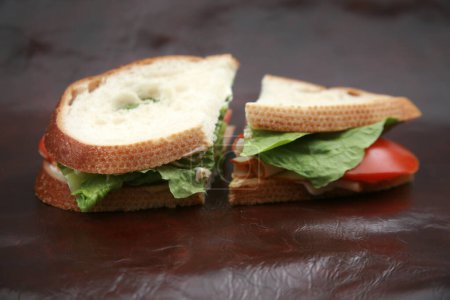 Téléchargez les photos : Sandwich aux dindes. Un sandwich à la laitue et à la tomate sur du pain aigre. Sandwich pour le déjeuner. Turquie Les sandwichs sont appréciés dans le monde entier par les personnes affamées. Sandwich à la dinde fait maison. Heure du déjeuner. - en image libre de droit