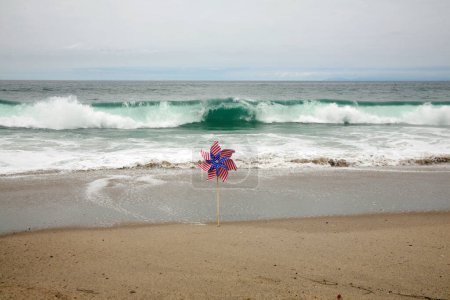 Téléchargez les photos : Drapeau américain. Une broche de drapeau américain dans la brise sur la plage. Drapeau américain sur la plage dans le sable. - en image libre de droit