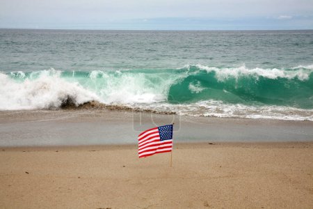 Téléchargez les photos : Drapeau américain. Une broche de drapeau américain dans la brise sur la plage. Drapeau américain sur la plage dans le sable. - en image libre de droit