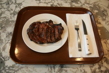 Téléchargez les photos : Un steak. Steak de boeuf. Viande rouge. Bifteck moyen juteux aux côtes de boeuf. Steak de boeuf grillé sur une assiette blanche. Viande du BBQ Grill. Surlonge grillée sur une assiette en céramique blanche. Le déjeuner est servi. Heure du dîner. - en image libre de droit