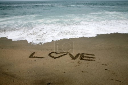 Téléchargez les photos : Amour écrit dans le sable de plage avec l'océan comme arrière-plan. - en image libre de droit