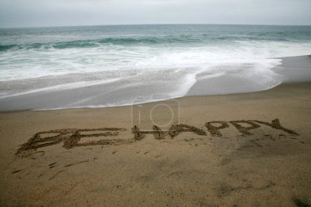 Foto de Ser feliz escrito en arena de playa con el océano como el fondo. - Imagen libre de derechos