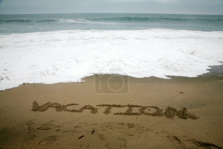 Foto de Vacaciones escritas en arena de playa con el océano como fondo. - Imagen libre de derechos