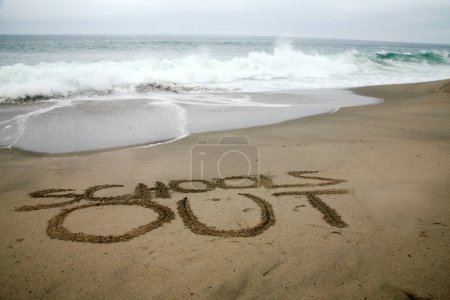 Téléchargez les photos : Écoles écrites dans le sable de plage avec l'océan comme arrière-plan. - en image libre de droit