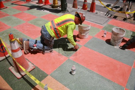 Foto de Los Ángeles. California - Estados Unidos - 18 de mayo de 2023: Sidewalk. Los contratistas instalan y detallan una caminata gris y roja en Los Ángeles, California. Los albañiles que trabajan con cemento y piedra completan un trabajo personalizado. - Imagen libre de derechos