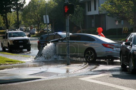 Photo for Lake Forest, California - USA - April 26, 2023: Major Car Accident. Car running over a Fire Hydrant and causing Flooding and a Water Hazard from a collision. Car Accident destroys a Fire Hydrant. - Royalty Free Image