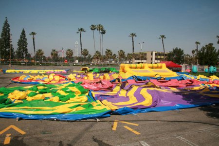 Foto de Buena Park, California - Estados Unidos - Abril - 27-2023: Juguetes inflables en un estacionamiento. juguetes inflables inflables sin inflar para los niños. castillos inflables coloridos del partido de los niños, diapositivas, y casas del rebote. - Imagen libre de derechos