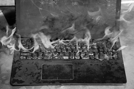 Photo for Burning laptop and keyboard, equipment fire due to faulty battery and wiring. Laptop burning in flames. Fire hazard. - Royalty Free Image