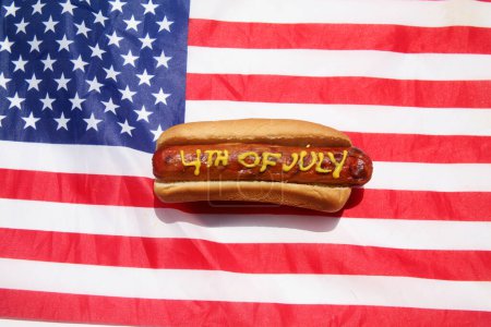 Photo for Hotdog. Mustard on patriotic hot dog. 4th of July Hot Dog. 4th of July written in Yellow Mustard on a Hotdog. USA Patriotic picnic holiday hotdogs. - Royalty Free Image