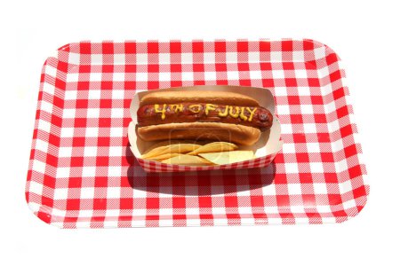 Foto de Perro caliente. Mostaza en salchicha patriótica. 4 de julio Hot Dog. 4 de julio escrito en Yellow Mustard on a Hotdog. Estados Unidos Patriotic picnic holiday hotdogs. - Imagen libre de derechos