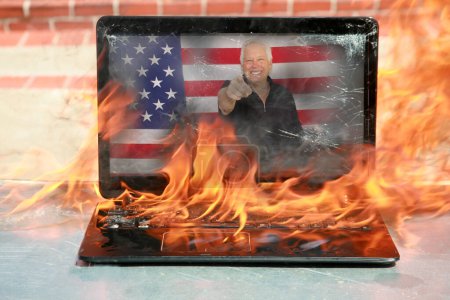 Photo for Burning laptop. A Man holds a cardboard sign that says IT'S GETTING HOT IN HERE. Hell Fire. Setting the world on fire. Laptop burning in flames. Fire hazard. Losing valuable data. Laptop Damage. - Royalty Free Image