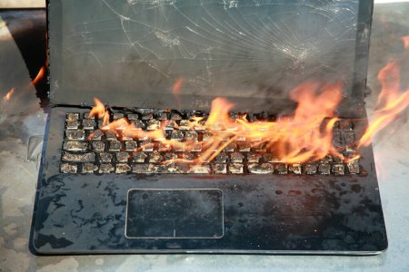 Photo for Burning laptop and keyboard. Laptop Computer on fire. Laptop burning in flames. Fire hazard. Losing valuable data. Computer Damage. Haunted laptop. Fire due to Evil. Computer in Hell. Halloween. - Royalty Free Image
