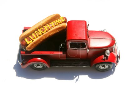 Foto de Hotdog con las palabras hora del almuerzo escritas en mostaza amarilla. Perros calientes para el almuerzo. Aislado sobre blanco. Hotdog en un camión rojo en su moño. - Imagen libre de derechos