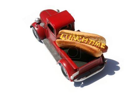 Téléchargez les photos : Hotdog avec les mots heure du déjeuner écrit en moutarde jaune. Hotdogs pour le déjeuner. Isolé sur blanc. Hotdog dans un camion rouge dans son chignon. - en image libre de droit