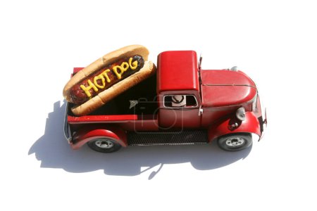 Téléchargez les photos : Hotdog avec les mots HOT DOG écrit en moutarde jaune. Hotdogs pour le déjeuner. Isolé sur blanc. Hotdog dans un camion rouge dans son chignon. - en image libre de droit