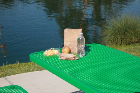 Téléchargez les photos : Déjeuner au lac avec sandwich, bouteille d'eau et pomme - en image libre de droit