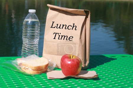 Téléchargez les photos : Déjeuner au lac avec sandwich, bouteille d'eau et pomme - en image libre de droit