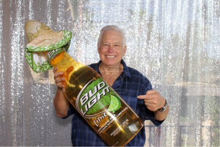 Foto de Lake Forest, California - Estados Unidos - 22 de julio de 2023: Photo Booth. Un hombre sonríe y posa para una foto divertida mientras está en una cabina de fotos en una fiesta. Las cabinas de fotos son divertidas para todos. Bud Light Beer Photo Booth. - Imagen libre de derechos