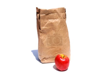 Foto de Bolsa de almuerzo de papel marrón y manzana roja aislada sobre fondo blanco - Imagen libre de derechos