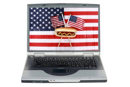 Téléchargez les photos : Ordinateur portable avec un hot dog américain classique et un drapeau américain. Célébration du 4 juillet avec Hot Dog - en image libre de droit