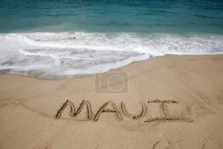 Foto de El nombre Maui escrito en arena en la playa con el fondo del Océano Pacífico. - Imagen libre de derechos