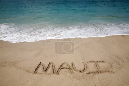 Téléchargez les photos : Le nom Maui écrit en sable sur la plage avec l'océan Pacifique Arrière-plan. - en image libre de droit
