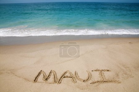 Photo for The name Maui written in sand on the beach with the Pacific Ocean Background. - Royalty Free Image