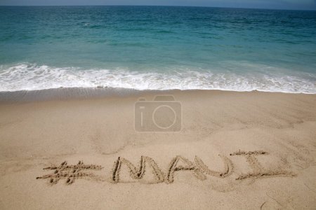 Téléchargez les photos : Le nom # Maui écrit en sable sur la plage avec l'océan Pacifique Arrière-plan. - en image libre de droit