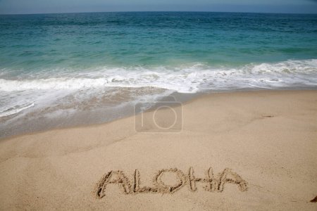 La palabra ALOHA escrita en la arena de la playa de Hawai.