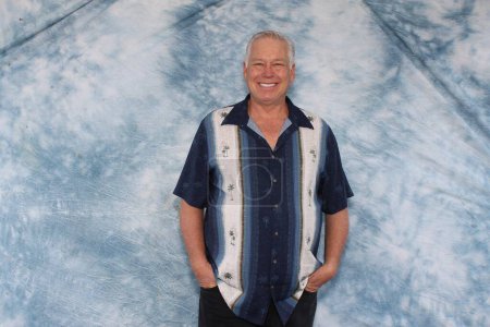 Foto de Un hombre sonríe mientras posa para que su foto sea tomada mientras está en una cabina de fotos en una fiesta. - Imagen libre de derechos