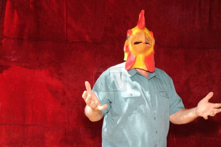 Téléchargez les photos : Une personne porte un masque de tête de poulet en caoutchouc tout en posant pour des photos dans une cabine photo - en image libre de droit