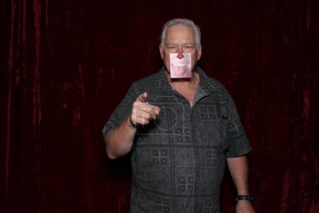 Photo for Adult man posing with paper smile for his picture to be taken while in a photo booth at a party - Royalty Free Image