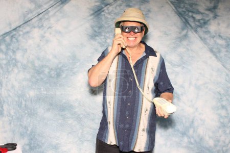 Téléchargez les photos : Un homme écoute un spot de vente sur son téléphone filaire Old School pendant qu'il se fait photographier dans une cabine photo - en image libre de droit
