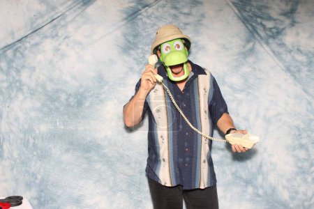 Téléchargez les photos : Homme en masque de crocodile et téléphone posant pour sa photo à prendre dans un photomaton lors d'une fête - en image libre de droit