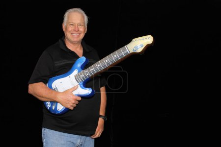 Téléchargez les photos : Senior homme pose dans le photomaton avec guitare jouet - en image libre de droit