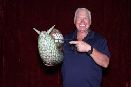 Téléchargez les photos : Un homme sourit alors qu'il tient un très grand escargot gonflable dans une cabine photo - en image libre de droit