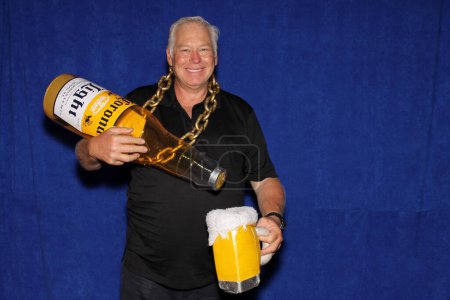 Photo for Lake Forest, California - USA - May 15, 2016: A man in chain holds a Inflatable Corona Beer Bottle while he smiles and poses for his pictures to be taken while in a Photo Booth - Royalty Free Image