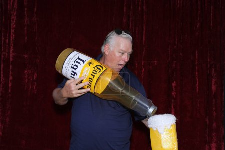 Foto de Lake Forest, California - Estados Unidos - 15 de mayo de 2016: Un hombre sostiene una botella inflable de cerveza Corona mientras sonríe y posa para que sus fotos sean tomadas mientras está en una cabina de fotos - Imagen libre de derechos