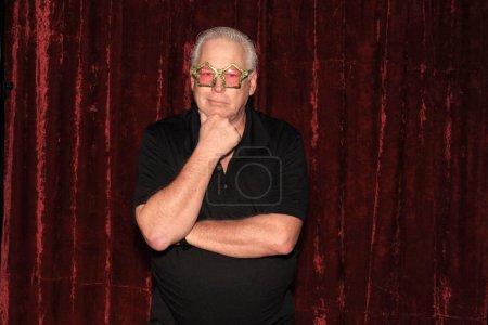Photo for Handsome middle aged man posing with yellow star glasses for his picture to be taken while in a photo booth at a party - Royalty Free Image